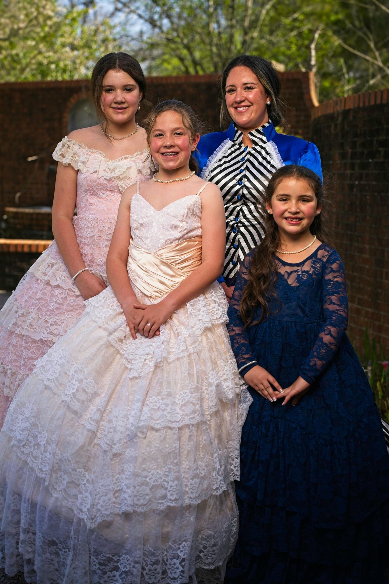 A group of young girls in dresses are posing for a picture.