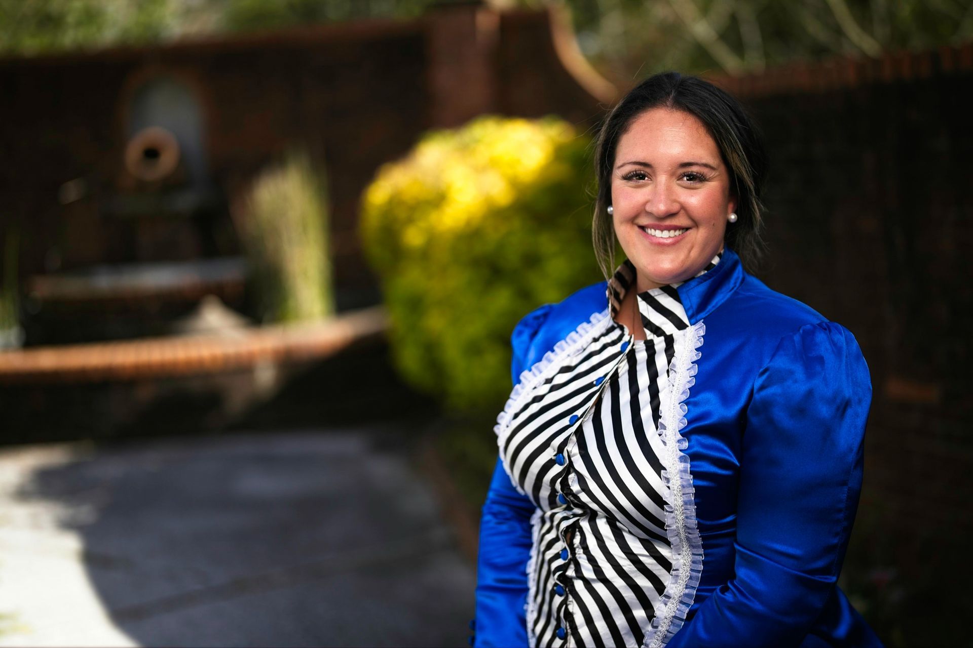A woman in a blue and white striped shirt is smiling for the camera.