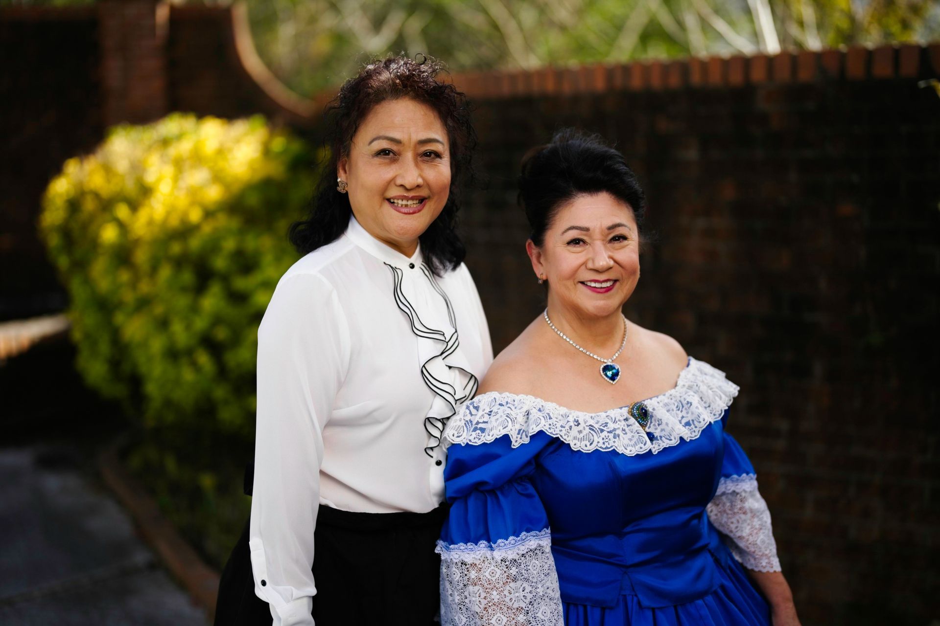 Two women are posing for a picture together and one is wearing a blue dress.