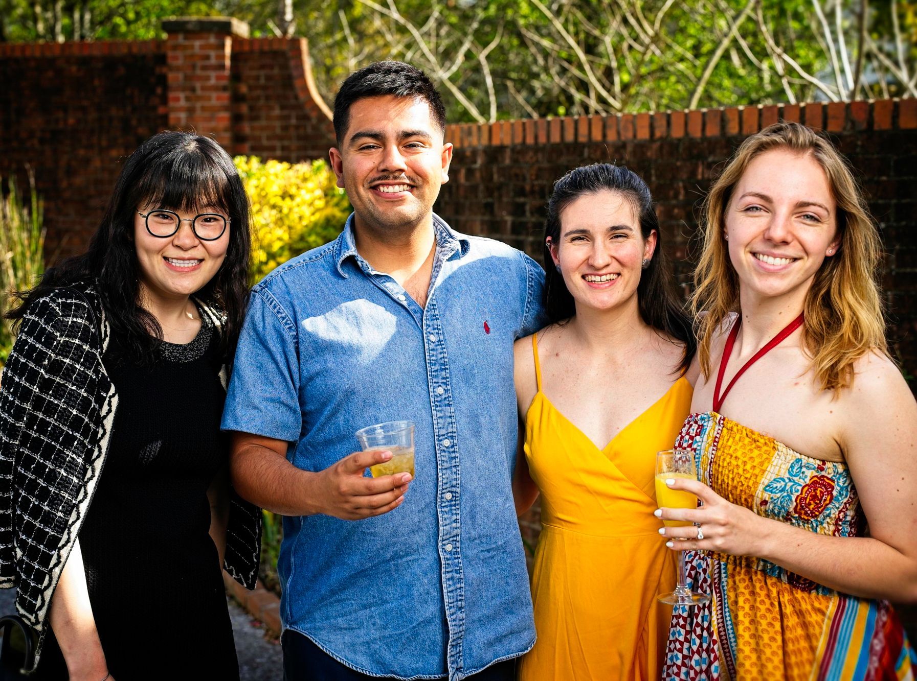 A group of people are posing for a picture while holding drinks.