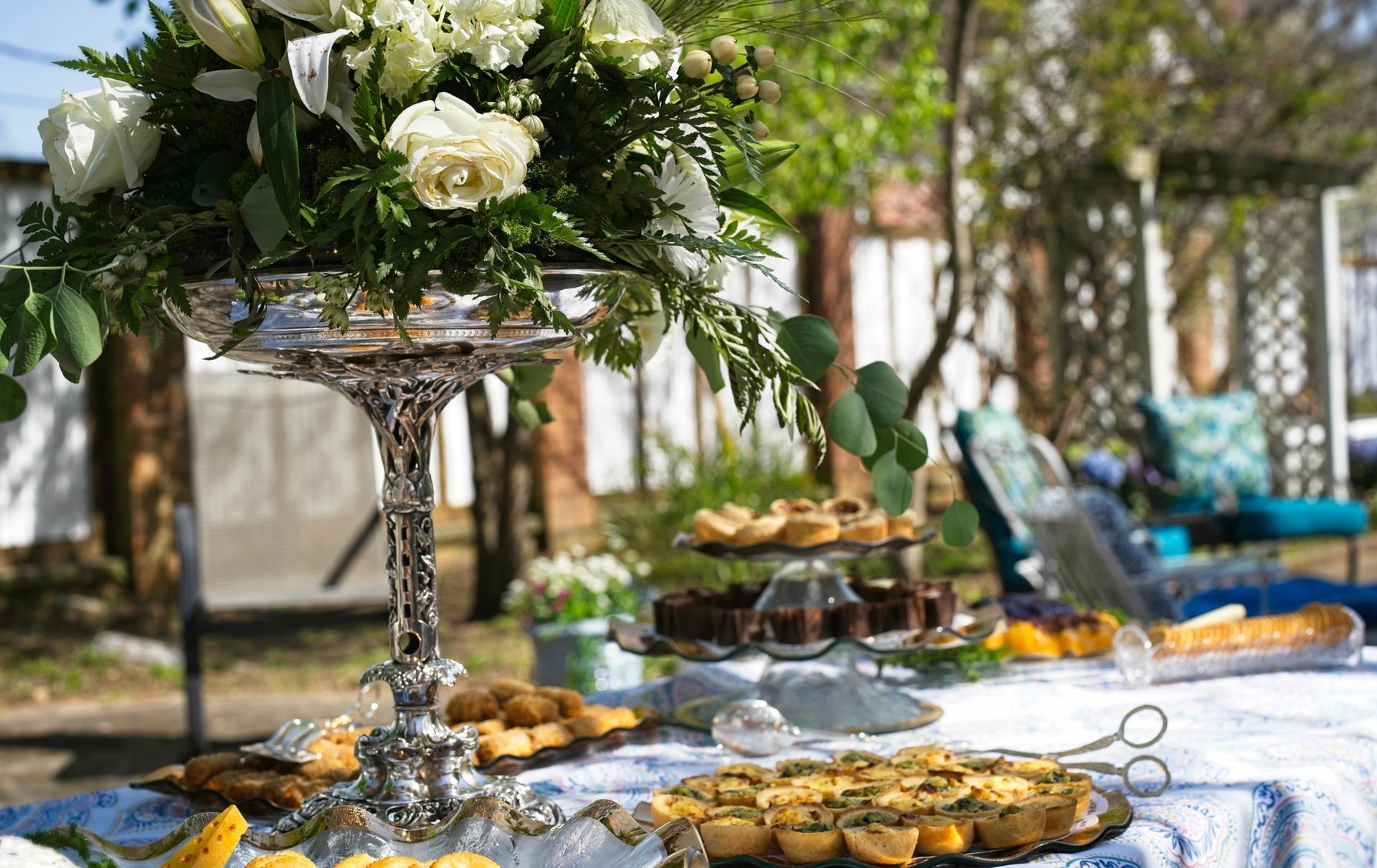 A table with a vase of flowers and plates of food on it.