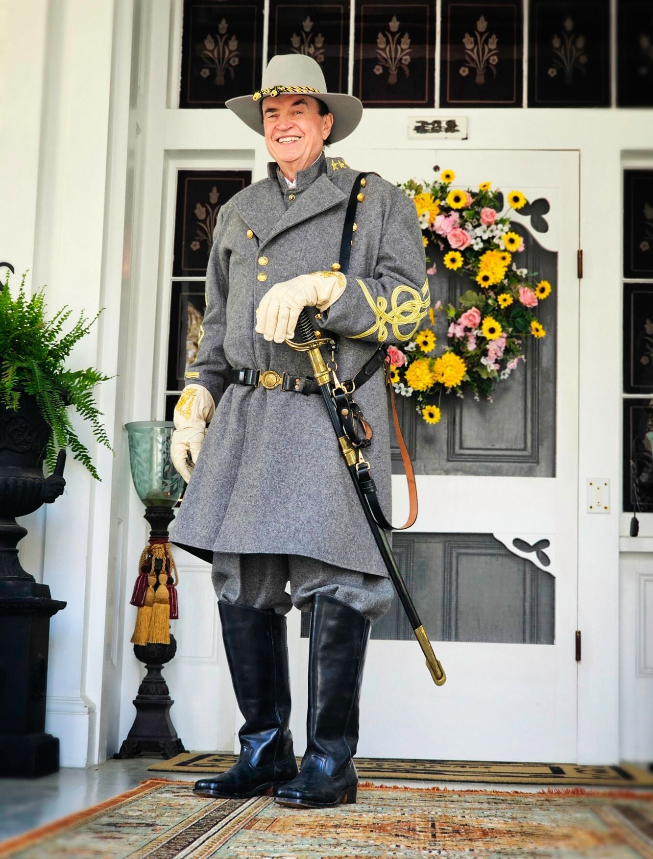 A man in a military uniform is standing in front of a door with a wreath on it