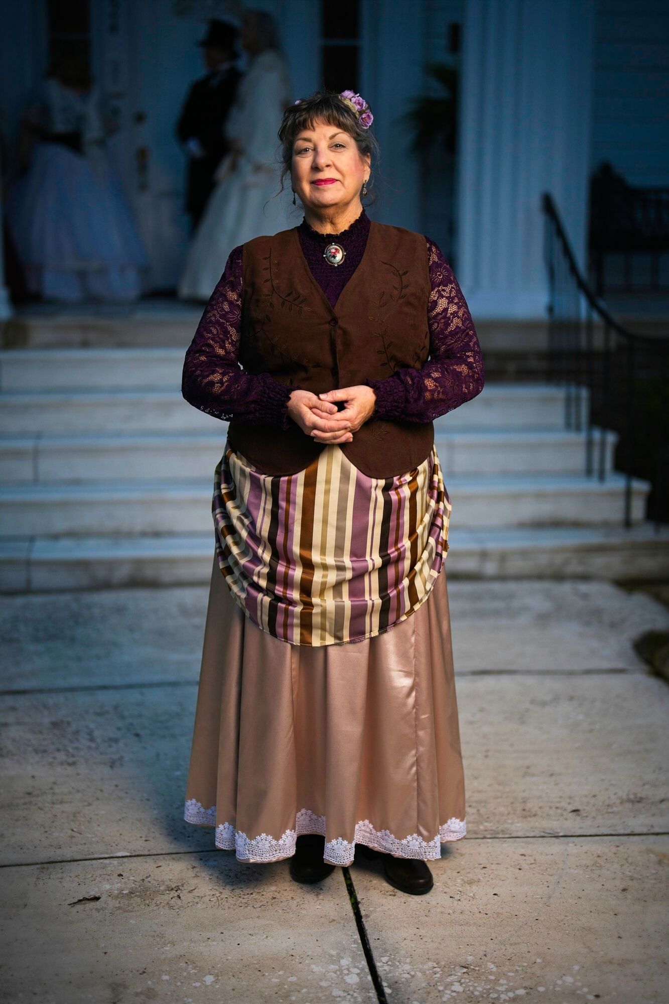 A woman in a costume is standing on a sidewalk in front of a building.