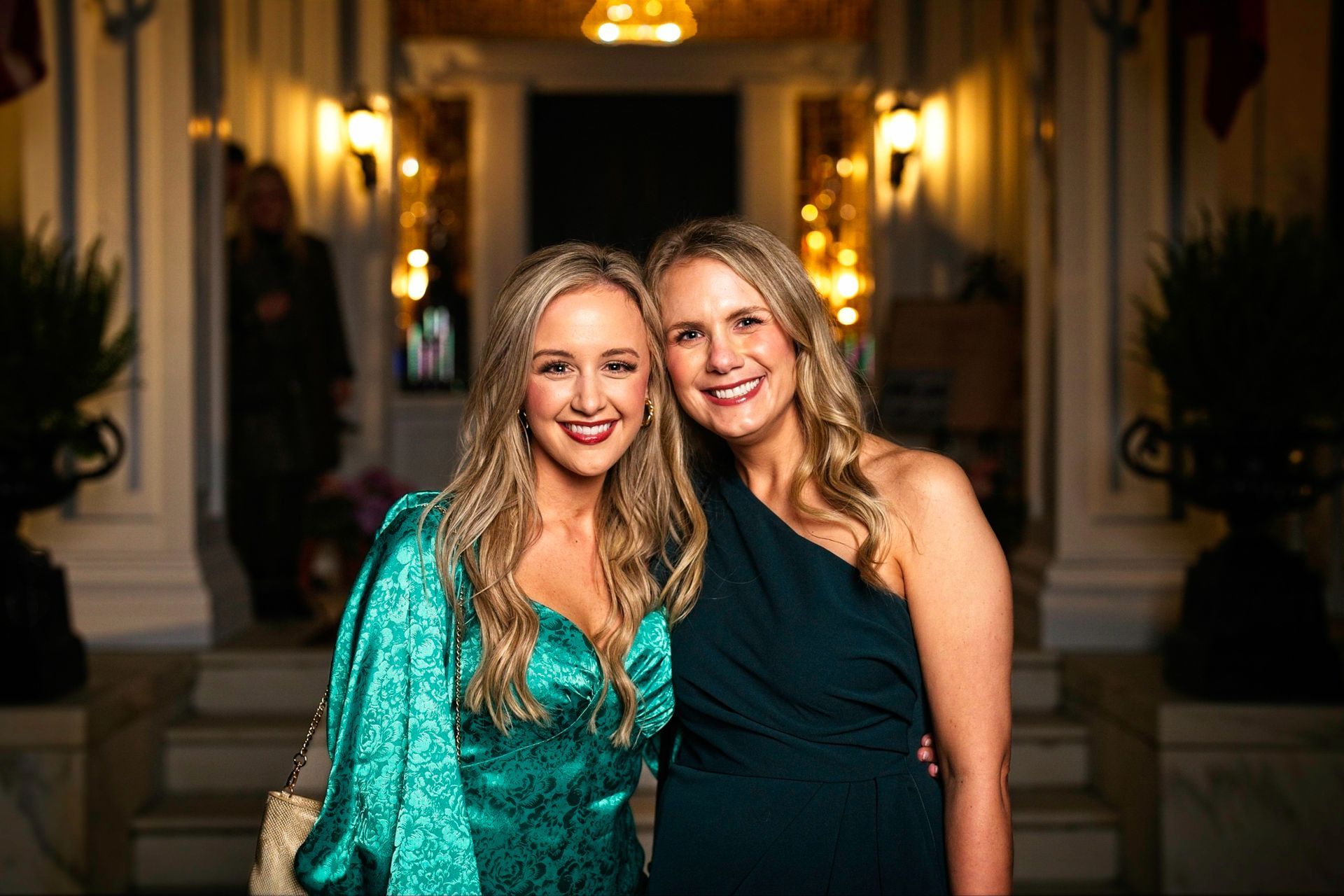 Two women in green dresses are posing for a picture in front of a building.