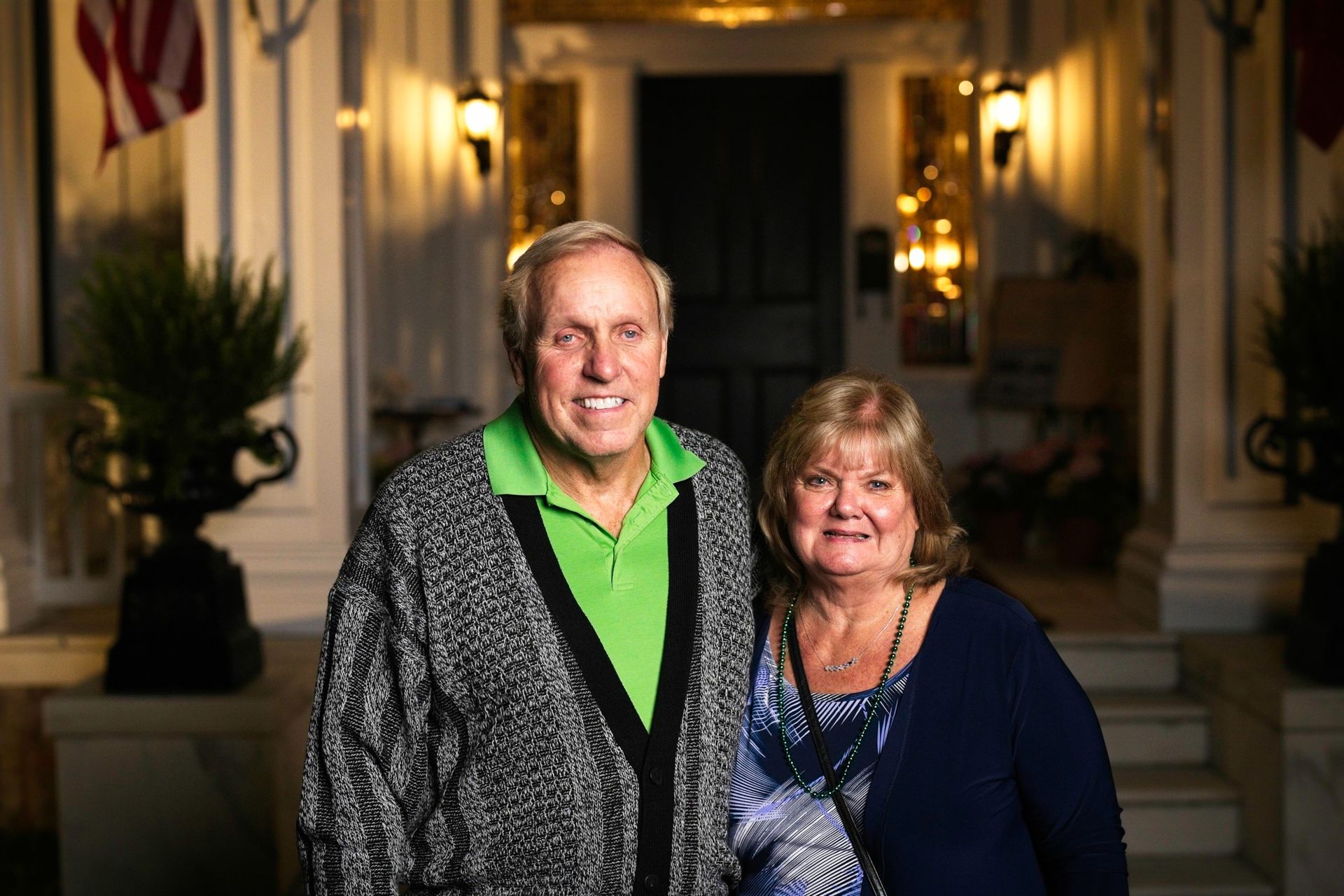 A man and a woman are posing for a picture in front of a house.