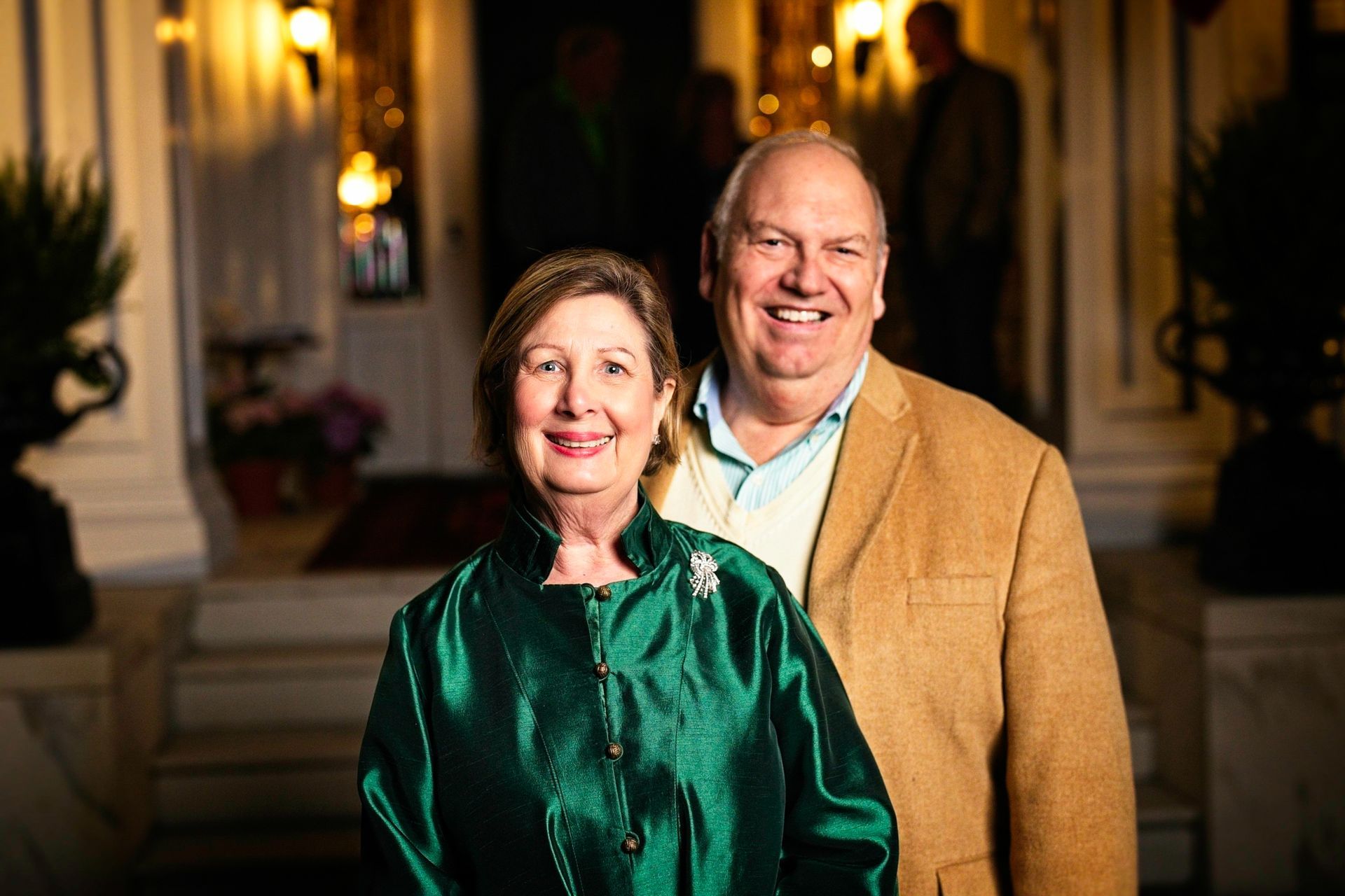 A man and a woman are posing for a picture in front of a house.