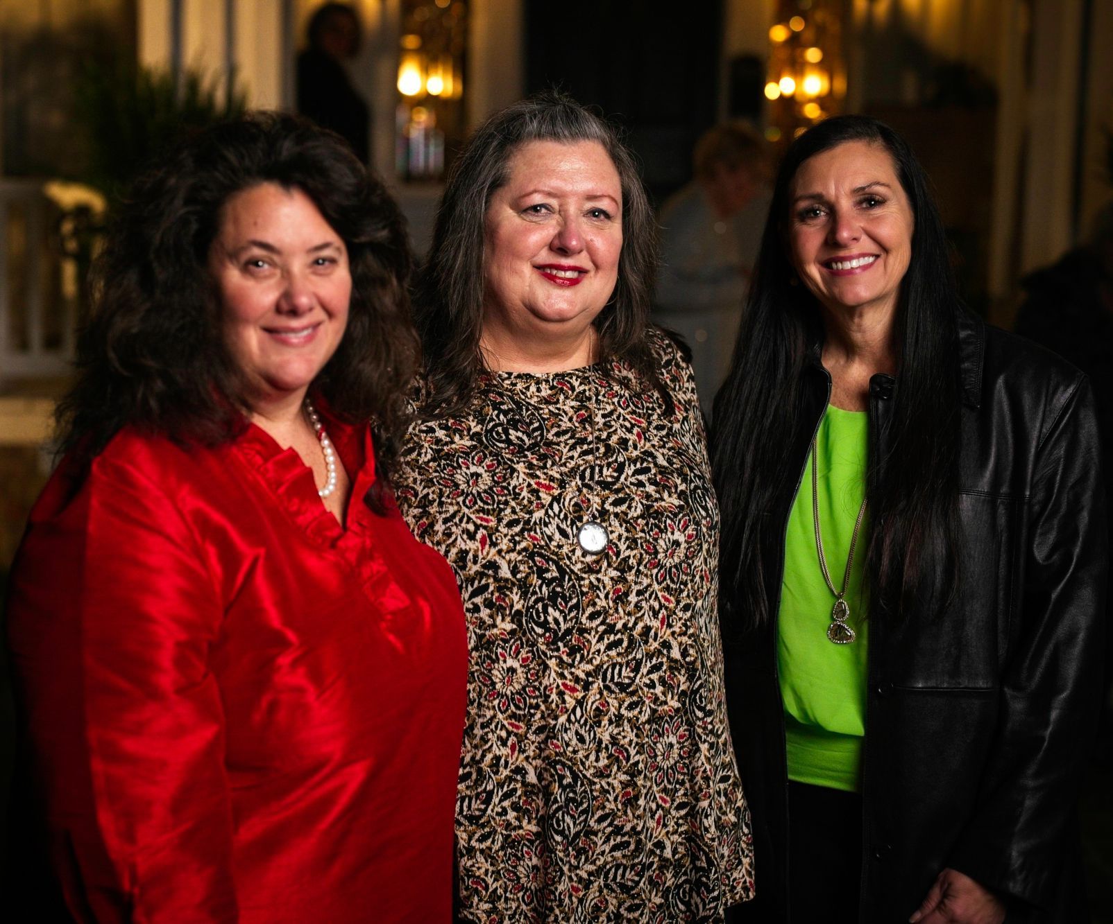 Three women are posing for a picture together and one of them is wearing a green shirt.