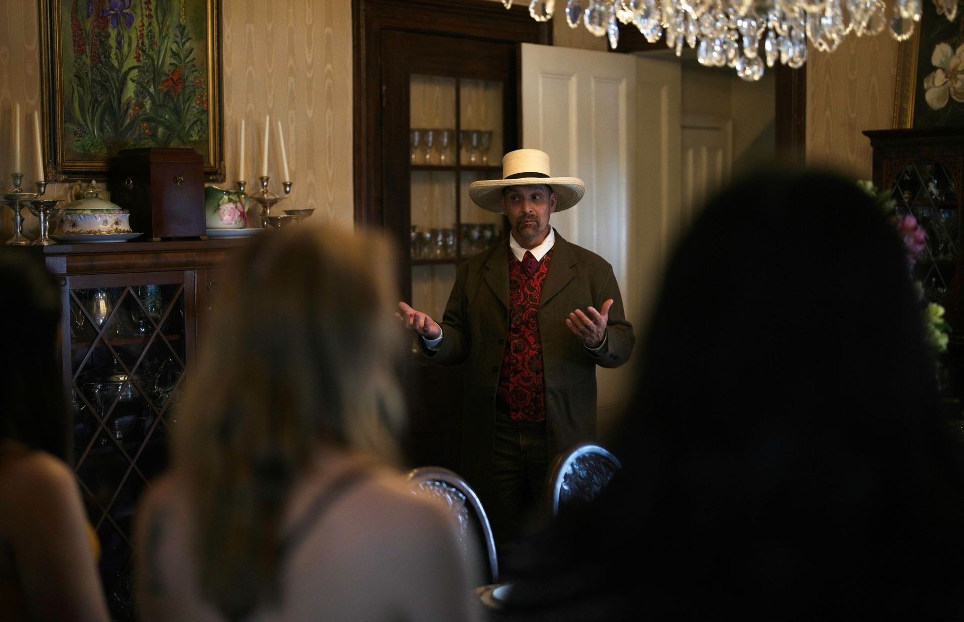A man in a hat is standing in front of a group of people.
