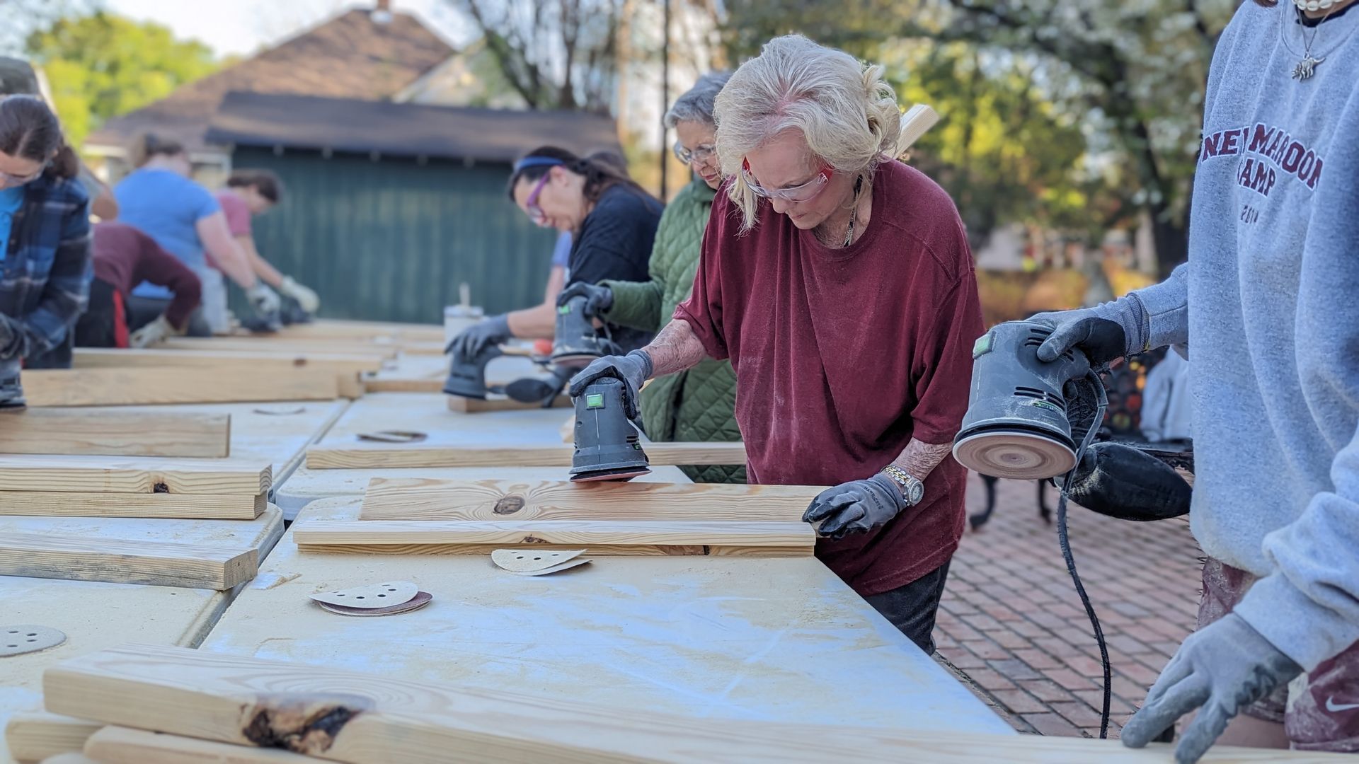 A group of people are working on a wooden table.