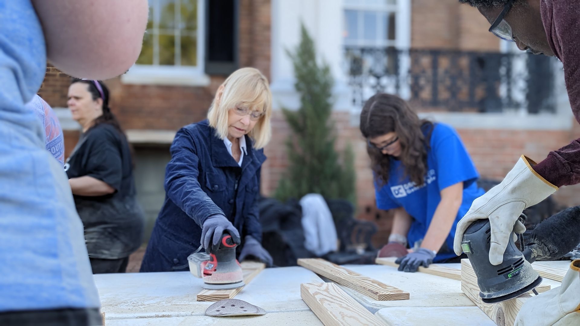 A group of people are working on a wooden table.