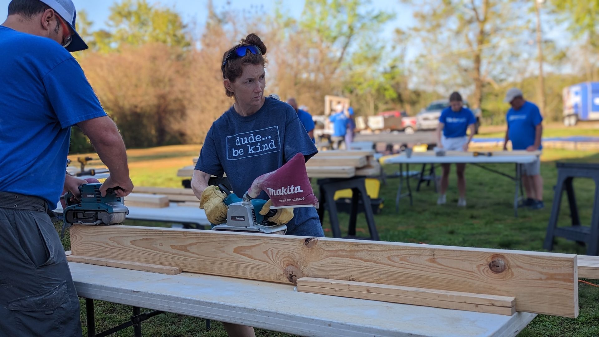 A man and a woman are cutting a piece of wood on a table.