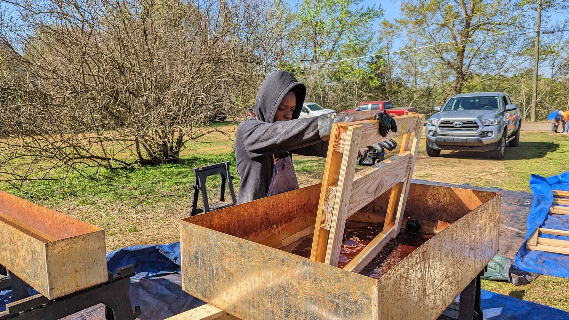 A man is working on a wooden structure in a field.