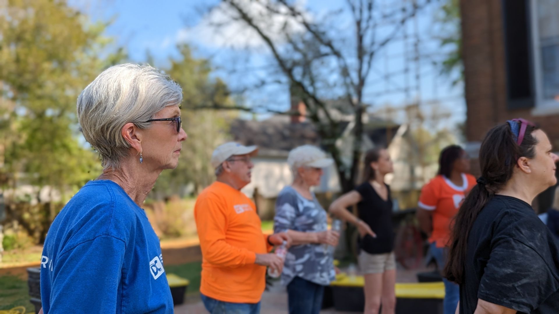 A woman in a blue shirt is standing in front of a group of people.