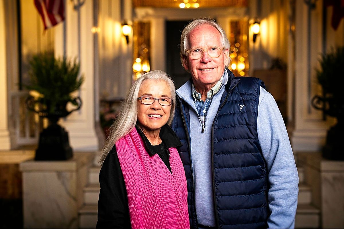 A man and a woman are posing for a picture in front of a building.