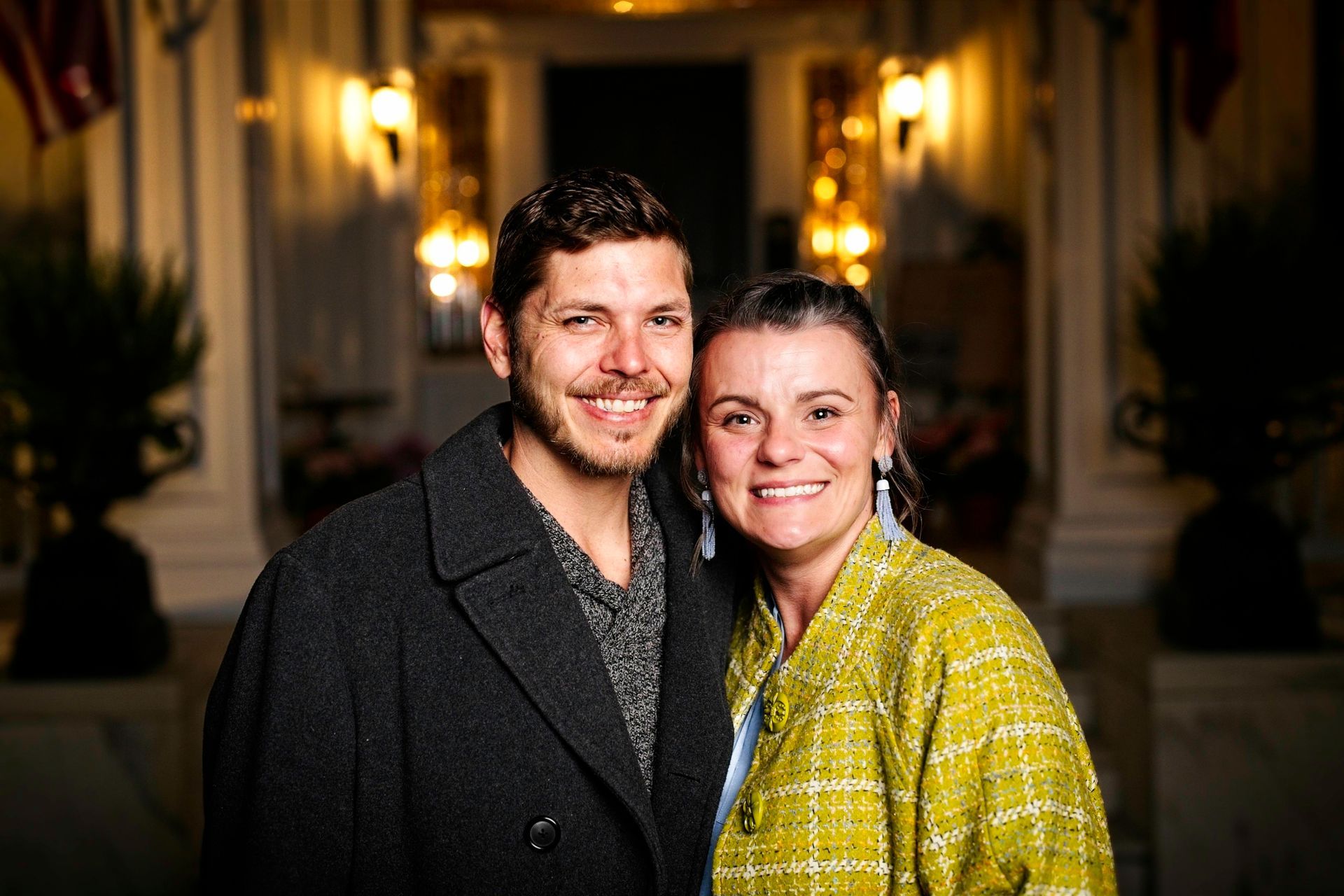 A man and a woman are posing for a picture in front of a building.