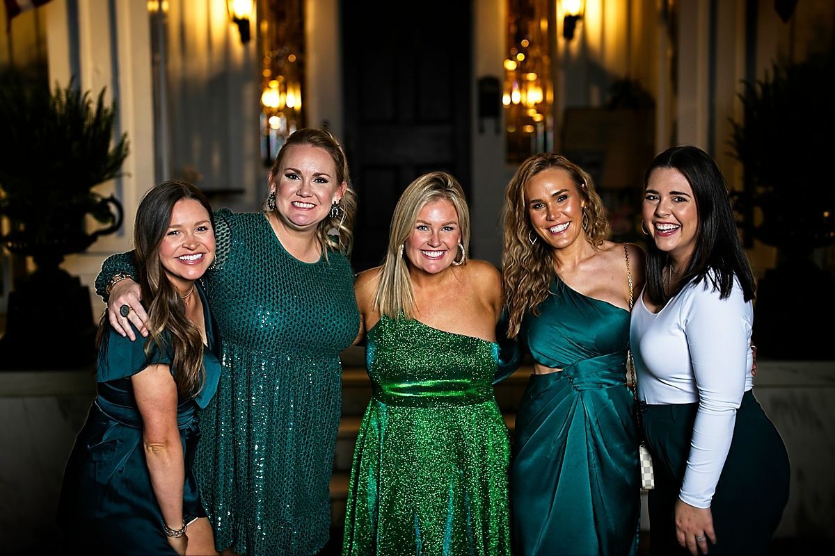 A group of women in green dresses are posing for a picture.