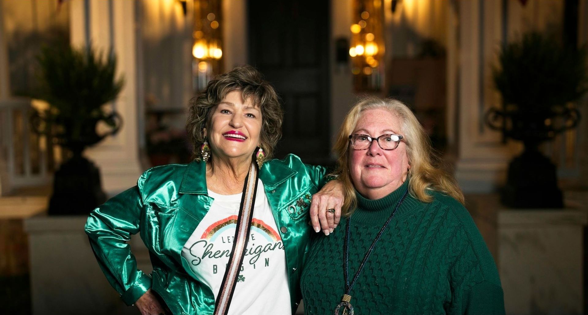 Two older women are posing for a picture together in front of a building.