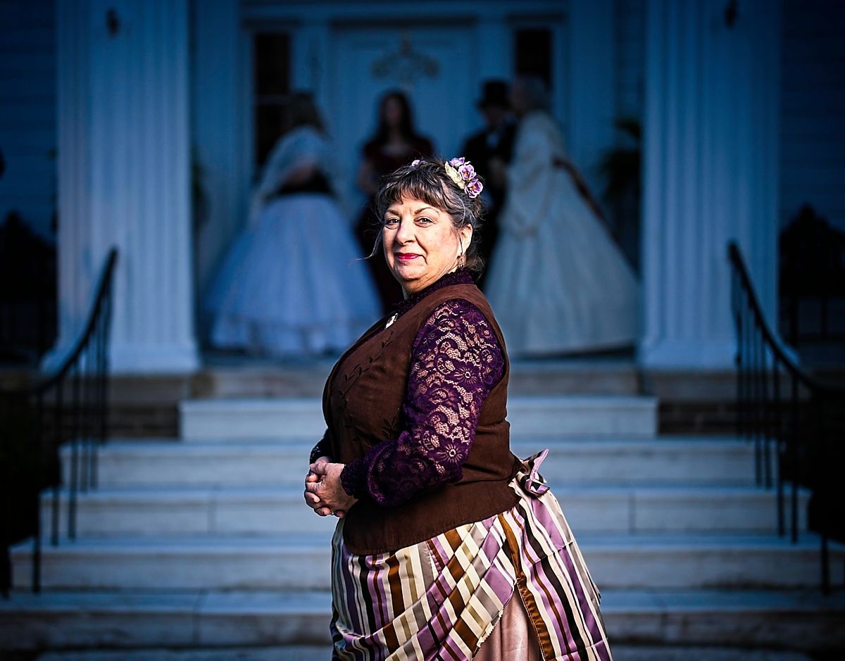 A woman in a purple dress is standing on the steps of a building.