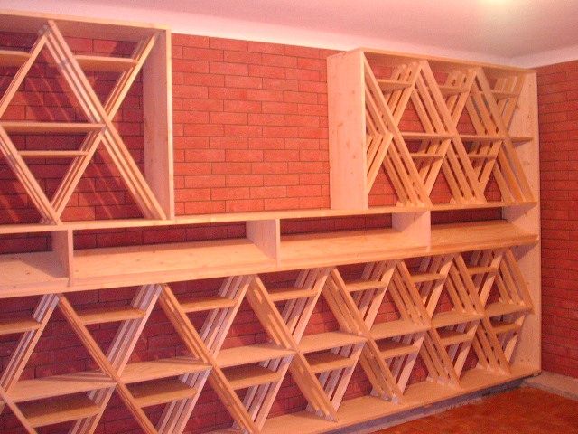 Étagères en bois avec compartiments triangulaires intégrées dans un mur de briques rouges.