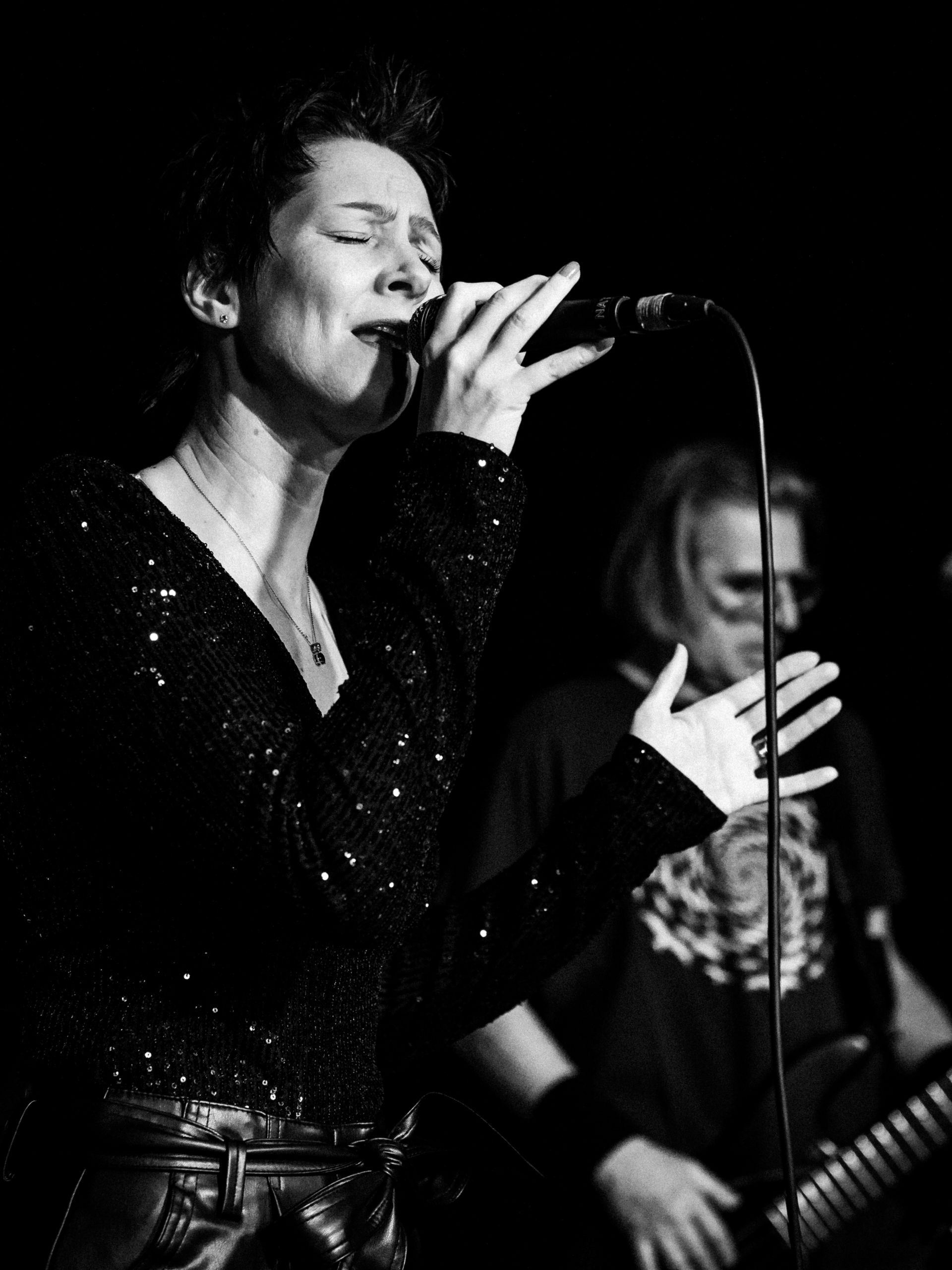 Auf einem Schwarz-Weiß-Foto singt Natalia Salamin in ein Mikrofon.