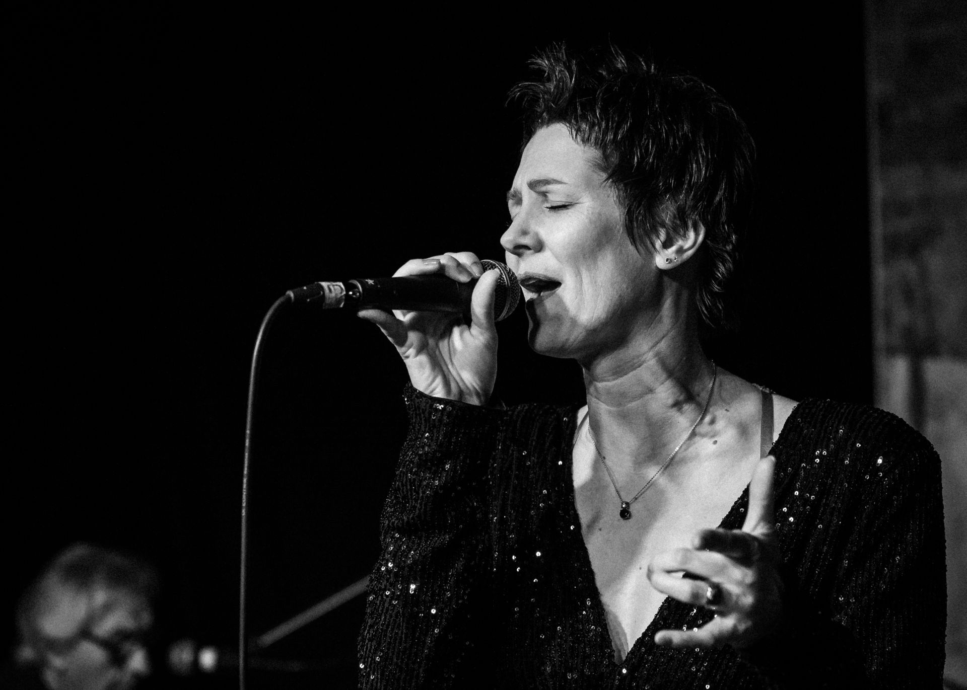 Auf einem Schwarz-Weiß-Foto singt eine Frau in ein Mikrofon.