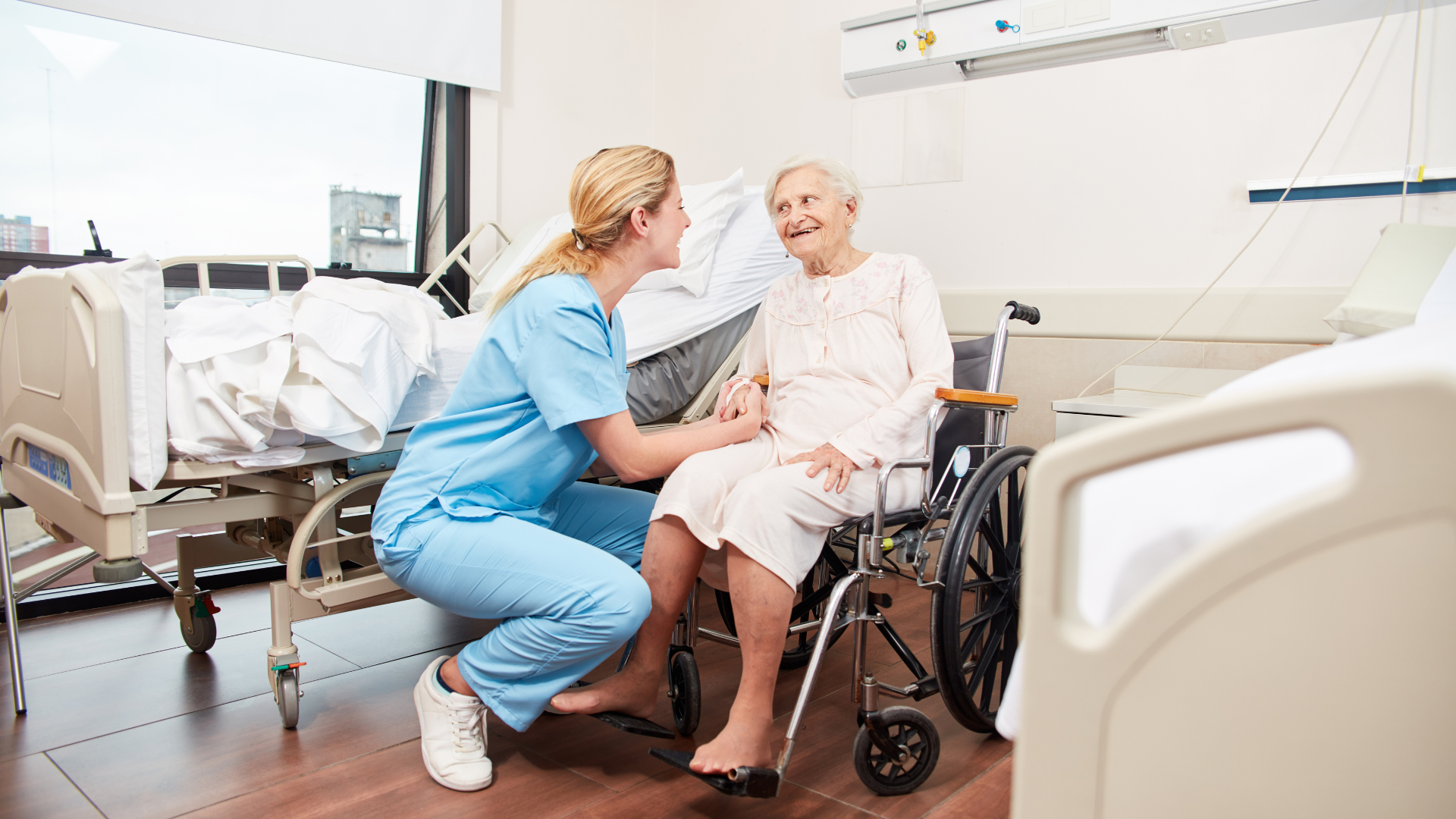Quality Life Services nurse in blue scrubs assisting elderly woman in wheel chair at Markleysburg nursing home