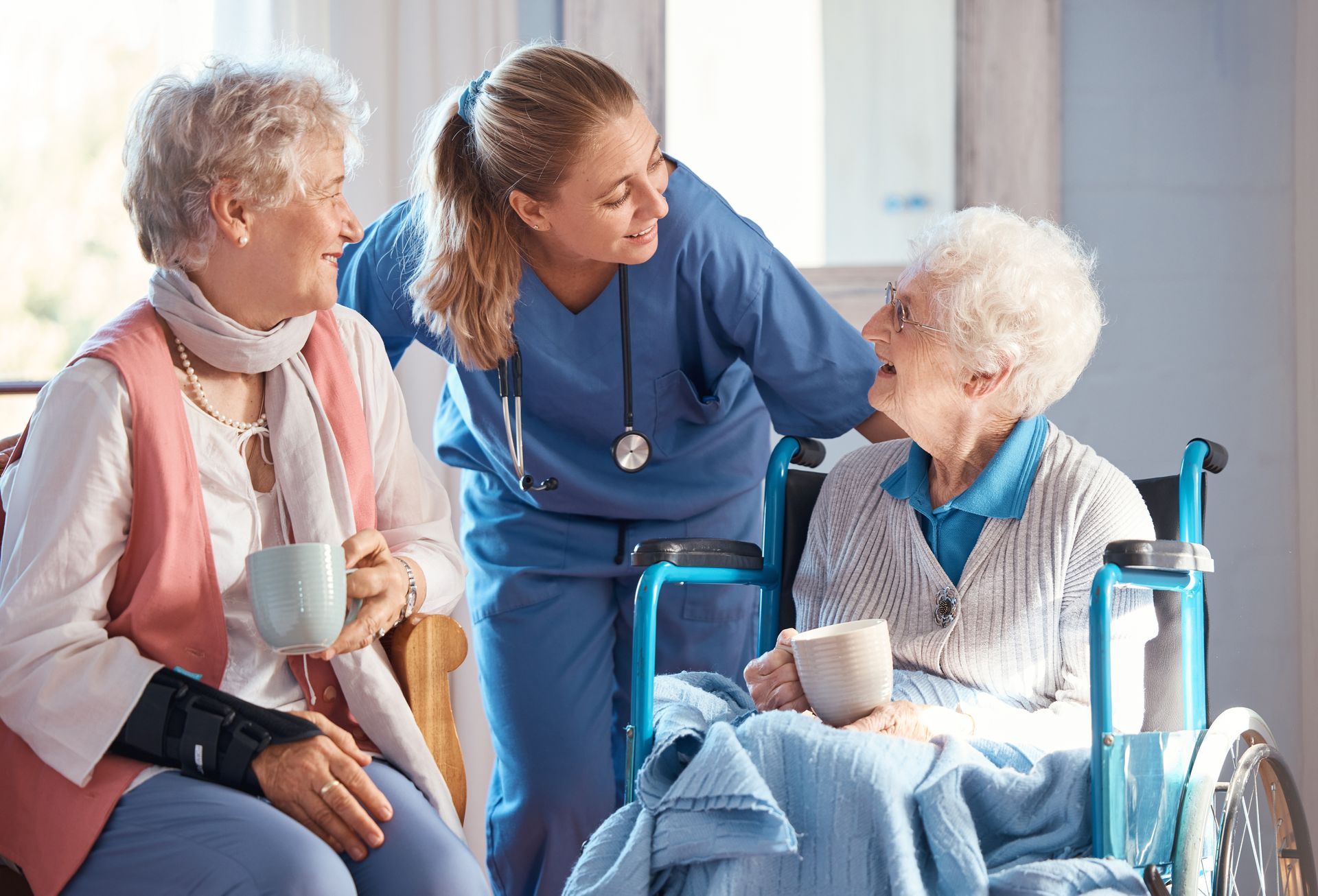 skilled nursing home facility nurse and elderly patients enjoying coffee in wheelchair