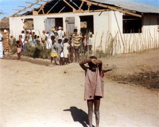 A little girl covering her face stands in front of a crowd of people