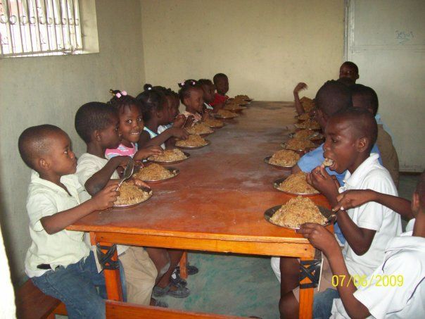 A group of children are sitting at a long table eating food