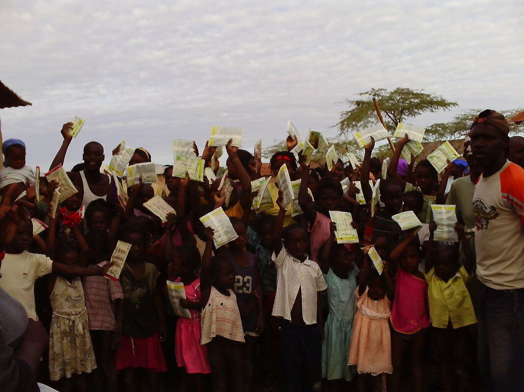 A group of children are holding up papers and one of them has the number 23 on their shirt