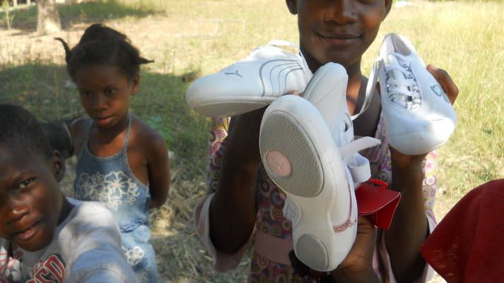 A woman is holding a pair of white shoes in her hands.