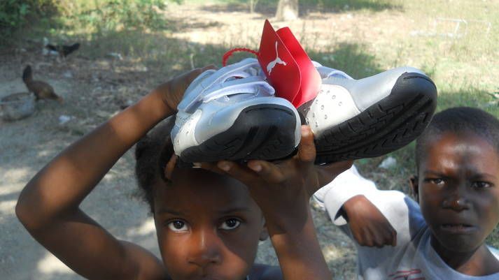 A little girl is holding a pair of shoes on her head