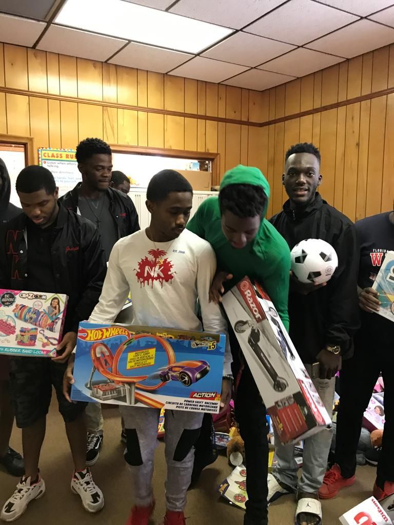 A group of young men are standing in a room holding toys.
