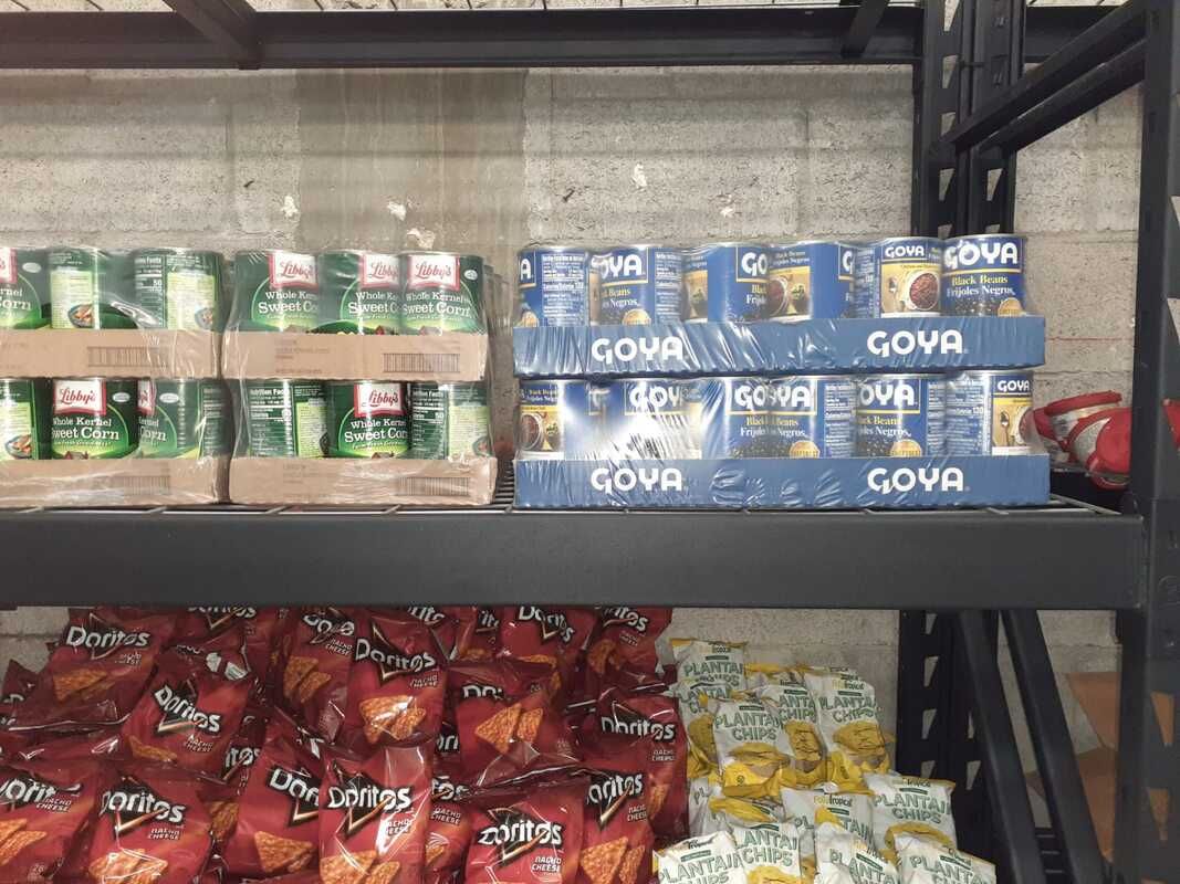 A shelf filled with a variety of snacks including doritos and goya