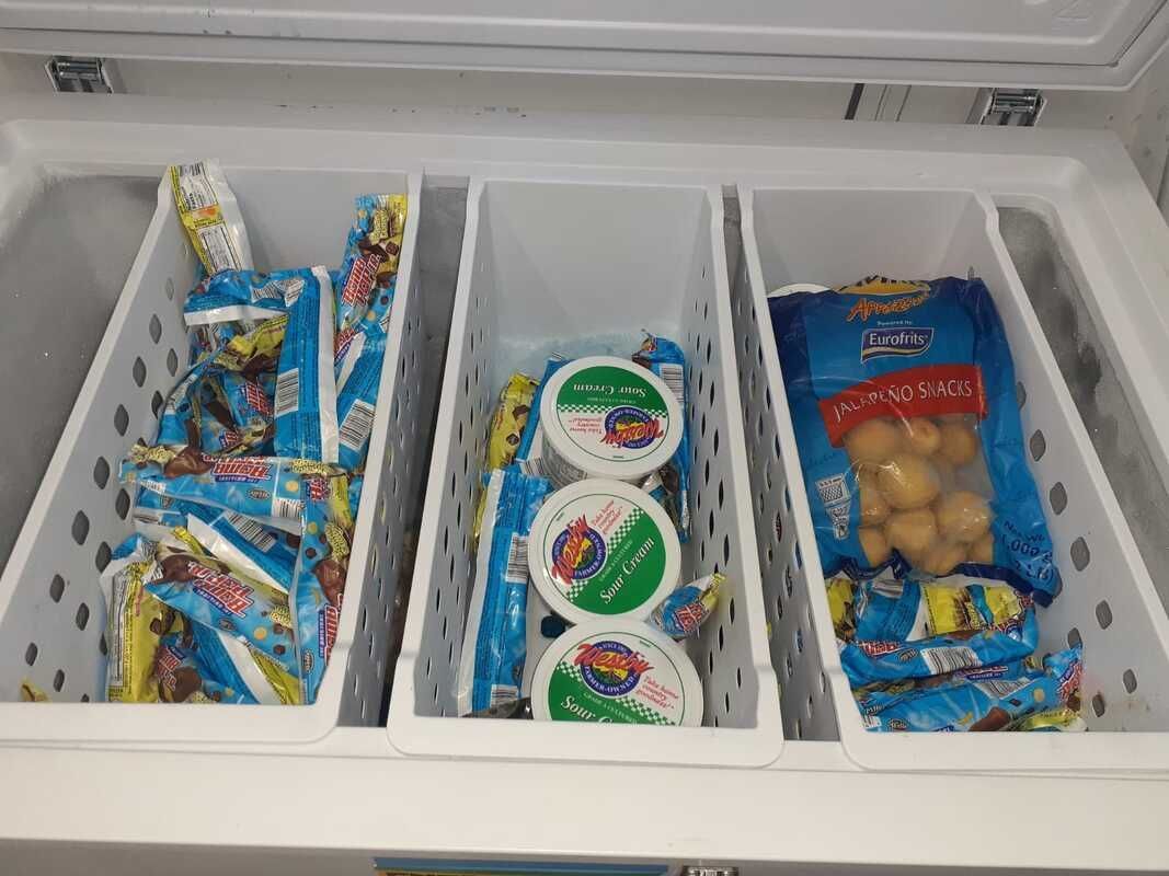 A freezer filled with ice cream , yogurt , and potatoes.
