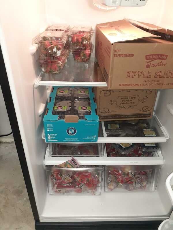 A refrigerator filled with boxes of apple slices and strawberries.