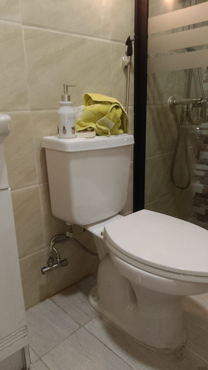 Inodoro blanco en un baño. Un dispensador de toallas y jabón está sobre el tanque.