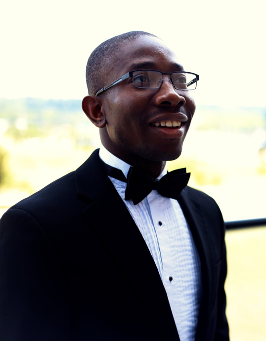 A man in a tuxedo and bow tie is smiling