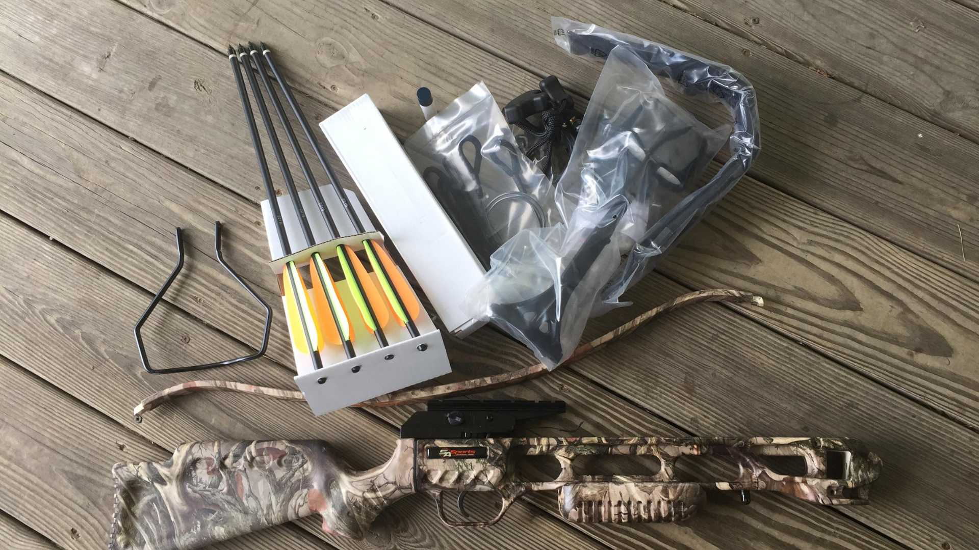 A bow and arrows are sitting on a wooden deck.