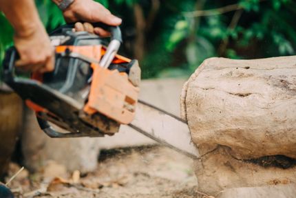 A person is using a chainsaw to cut a log.