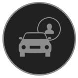 A gray icon of a car with a silhouette of a person inside a circle behind it, set against a dark circular background.