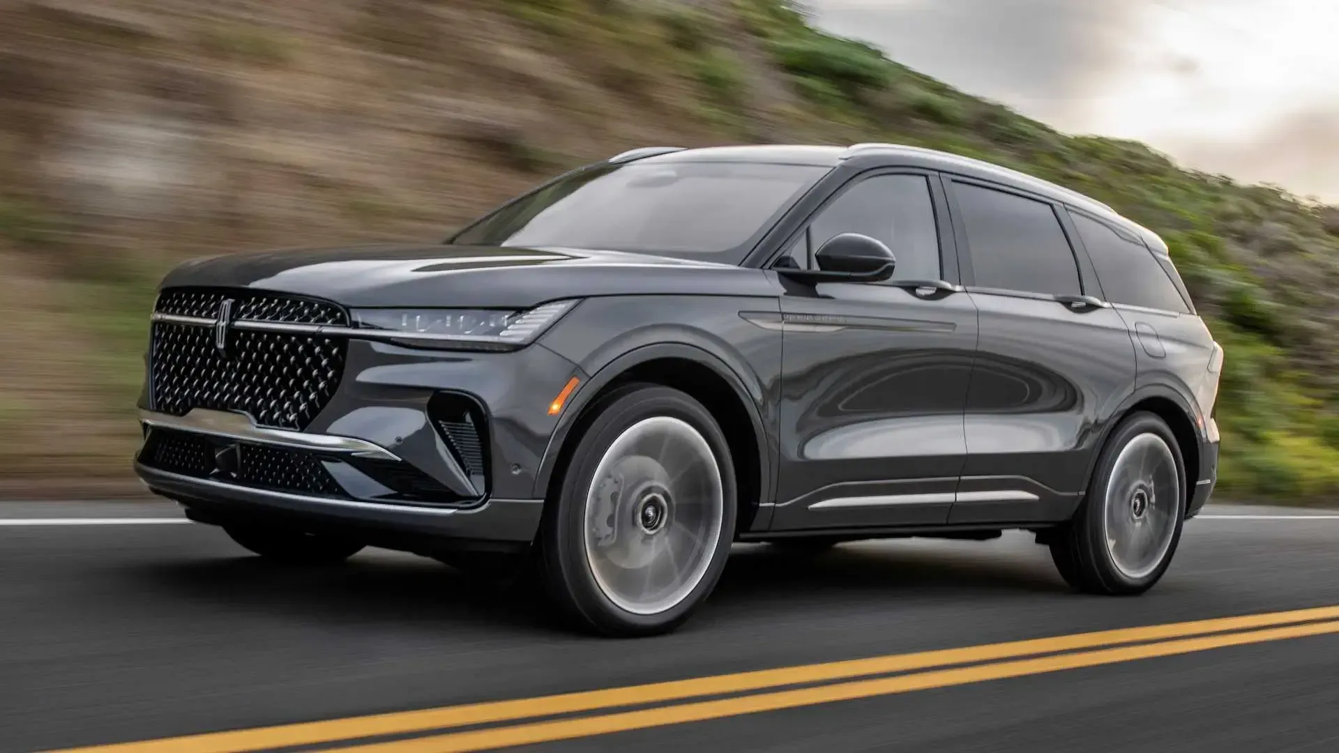 A black lincoln aviator is driving down a road.