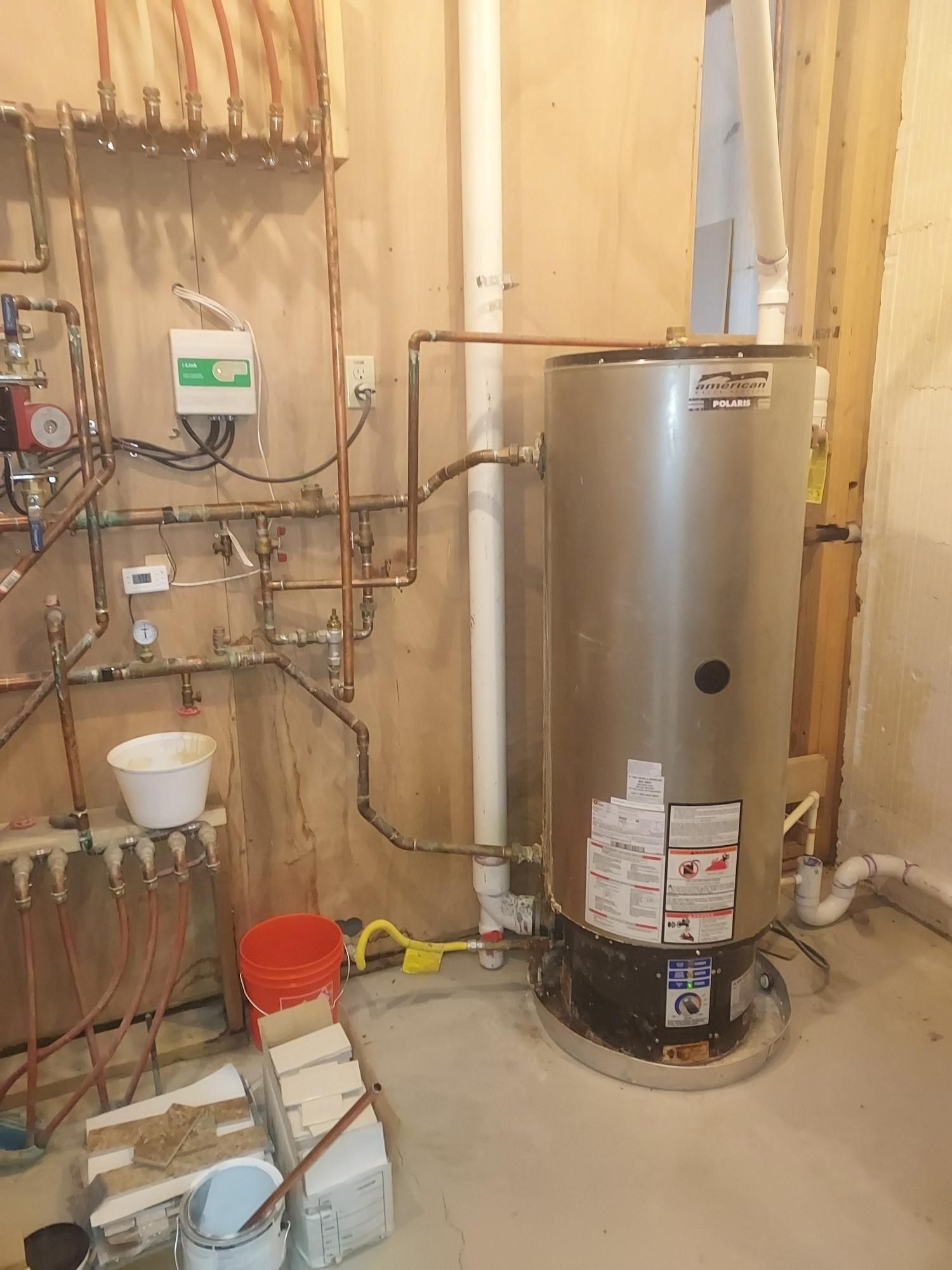 Water heater with copper pipes in a utility room.