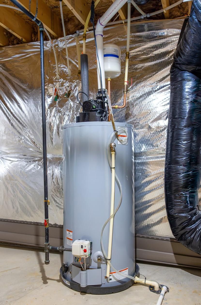 A tall gray water heater in a basement with metal ductwork and pipes.