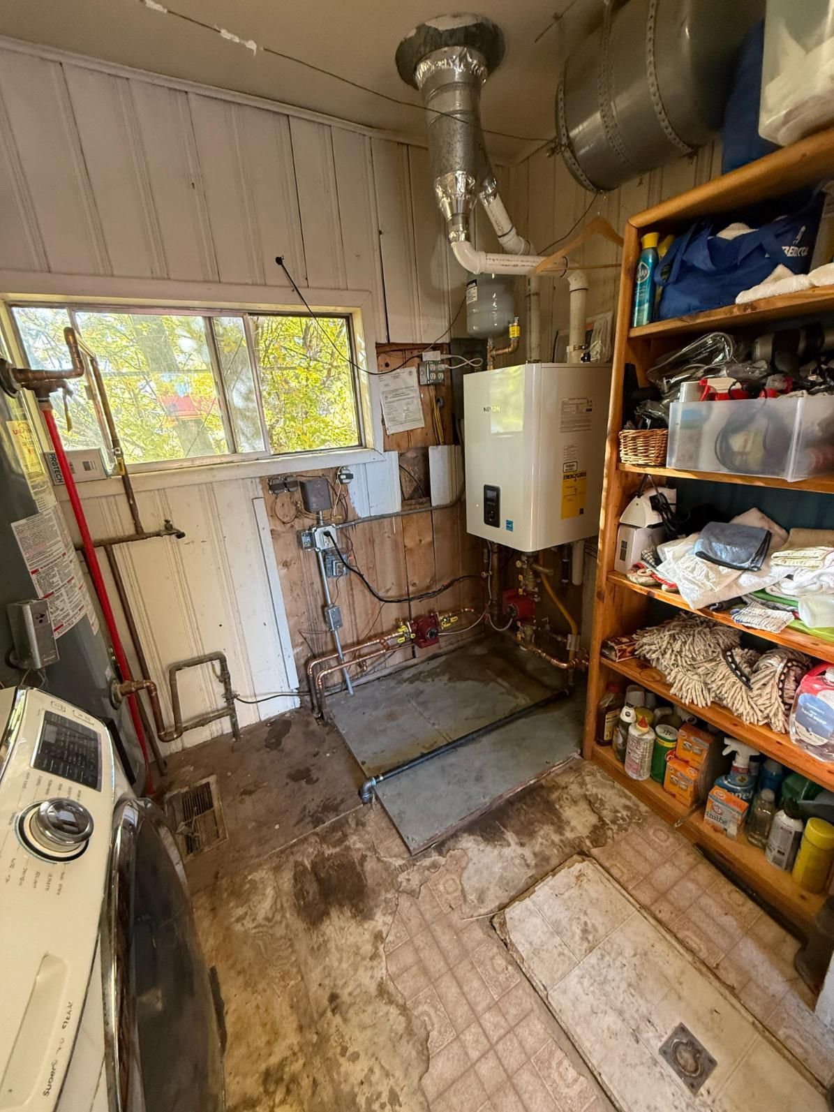 Laundry room with a water heater, shelves, window, and a washing machine.