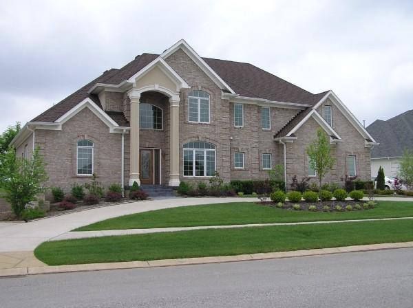 Large brick house with a brown roof, two stories, and a circular driveway.