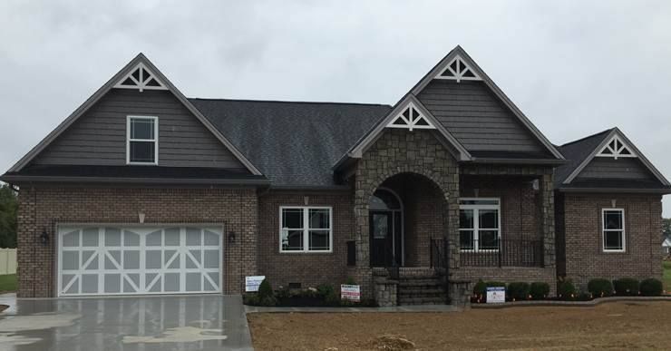 Brick house with multiple gables, arched entry, and a two-car garage. Overcast sky.