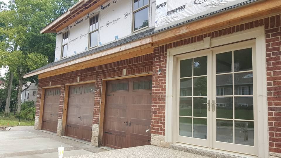 Brick building with three garage doors, french doors, and windows under construction.