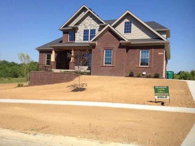 Two-story brick house with stone accents on a sunny day. New lawn and 