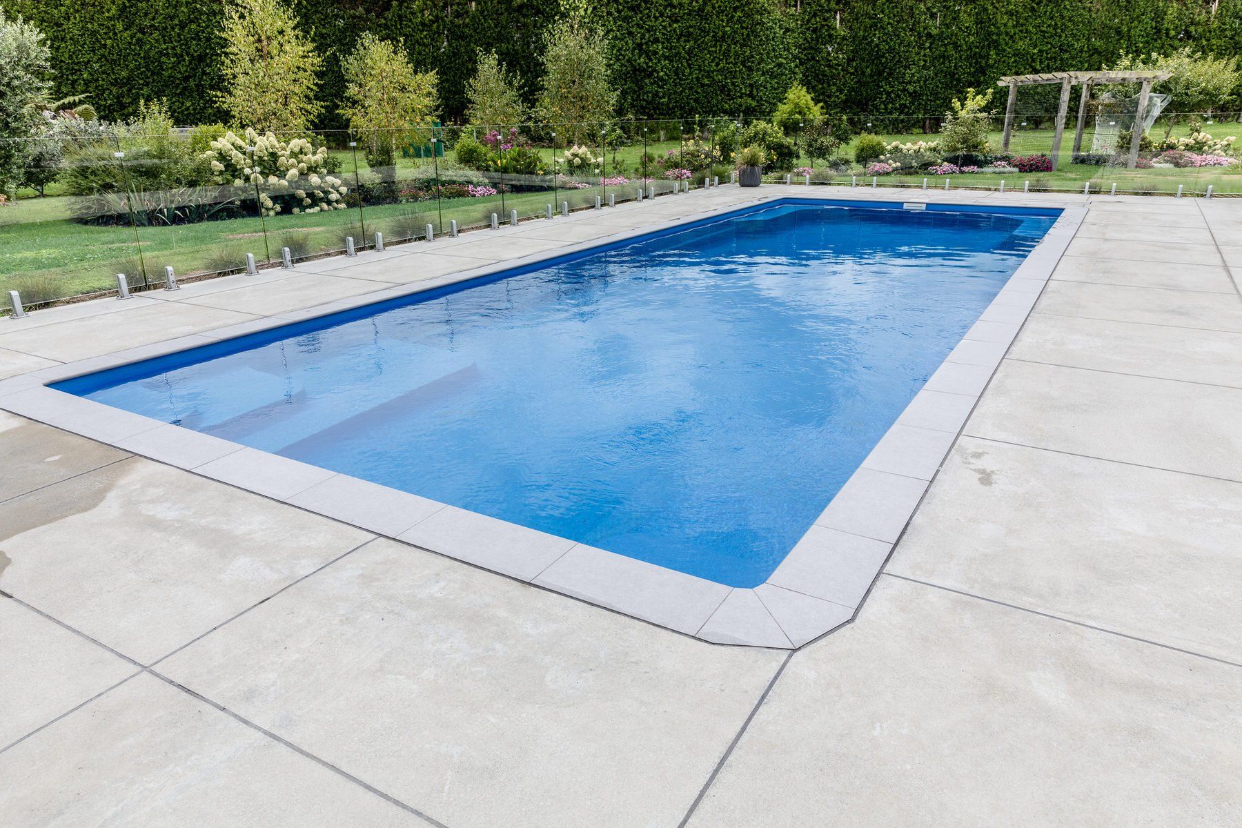 A large swimming pool is sitting on top of a concrete patio. Poolcorp Pools Auckalnd